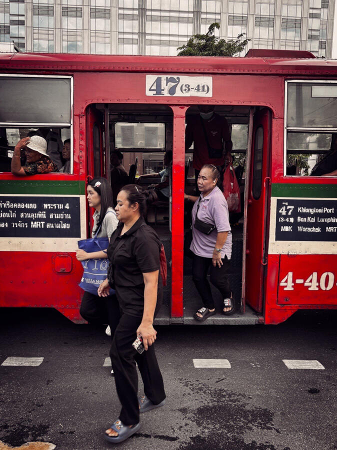 Off the Bus · Bangkok, Thailand Passengers getting off a red city bus as pedestrians cross the street in Bangkok, Thailand.