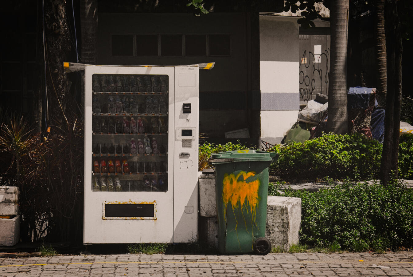 Urban Contrasts A vending machine stands beside a weathered rubbish bin on a quiet street in Da Nang, Vietnam. An ordinary urban scene where convenience, neglect and everyday life exist side by side.